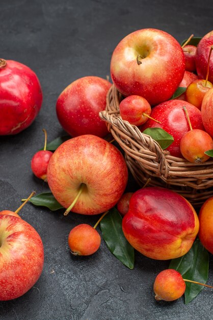 Side view fruits basket of apples cherries leaves nectarine pomegranates