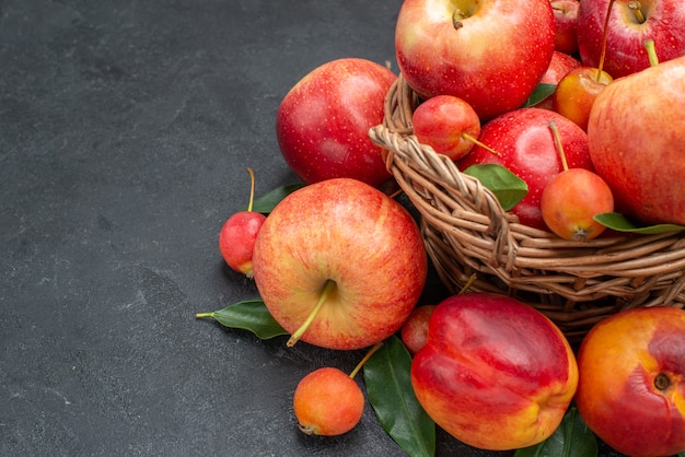 Side view fruits the wooden basket with apples cherries nectarine with leaves