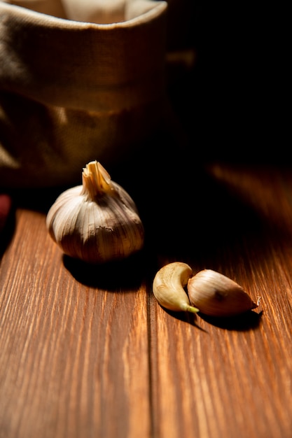 Side view of garlic on a wooden table on dark table