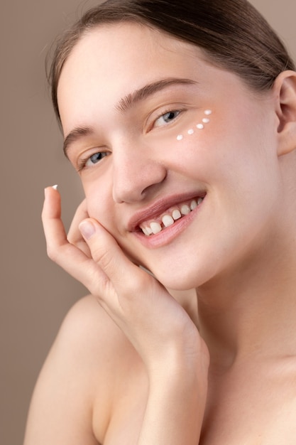 Free photo side view girl applying eye cream