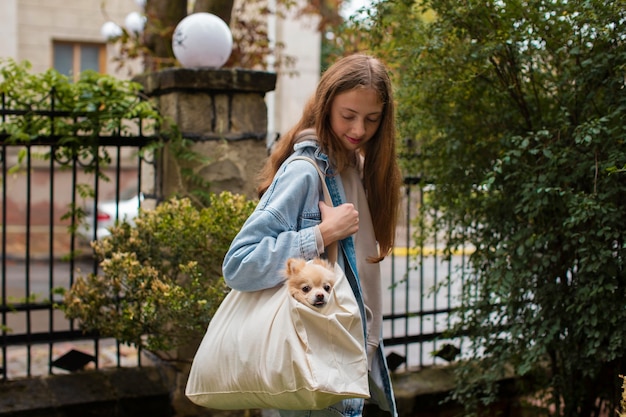 Free Photo side view girl carrying bag with dog