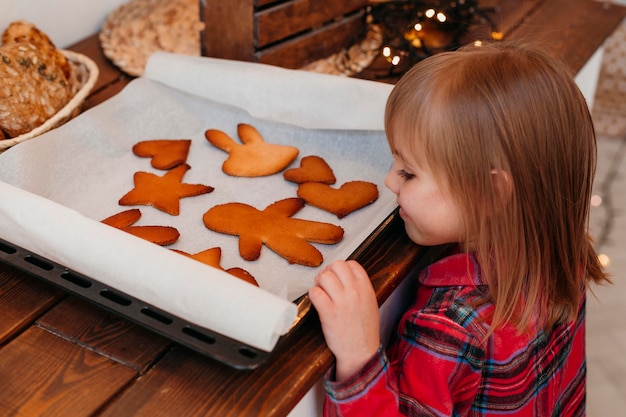 Side view girl checking baked christmas cookies