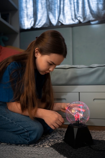 Side view girl interacting with a plasma ball