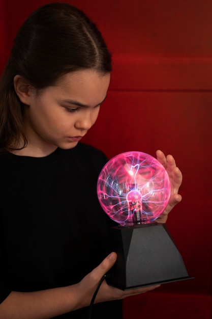 Side view girl interacting with a plasma ball