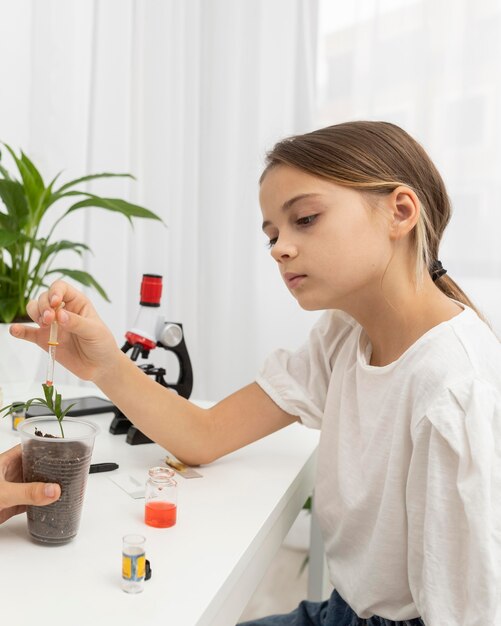 Side view of girl learning about science with plant