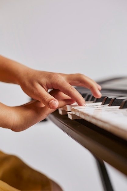 Free photo side view of girl learning how to play the electronic keyboard