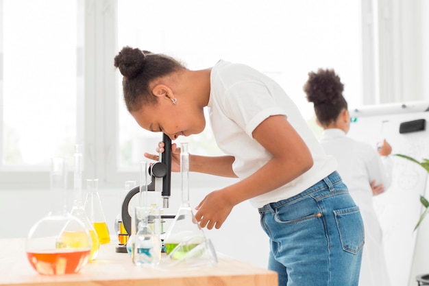 Side view of girl looking through microscope