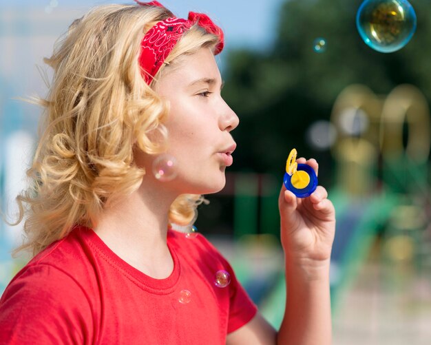 Side view girl playing with bubble blower