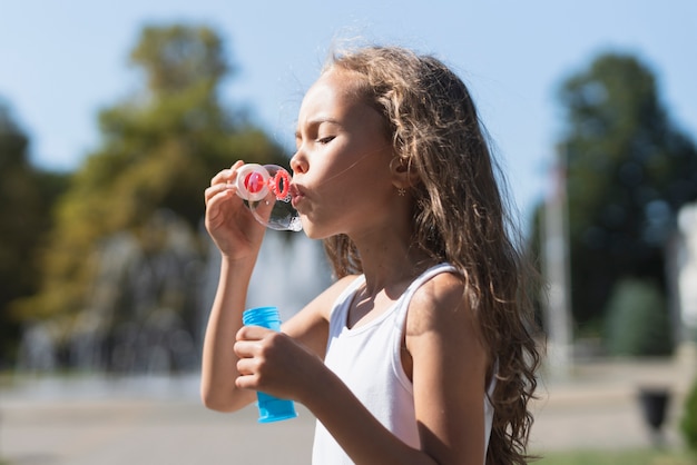 Side view of girl playing with soap bubbles