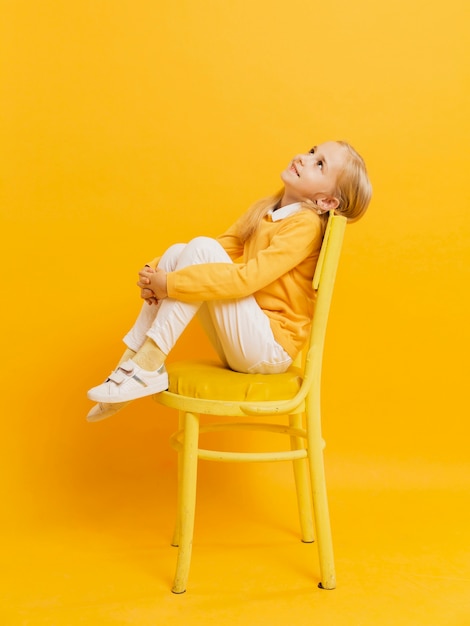 Free photo side view of girl posing on chair while looking up