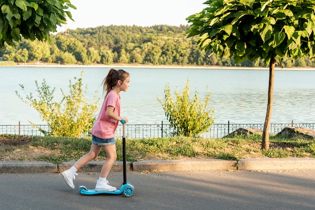 Side view of girl riding blue scooter