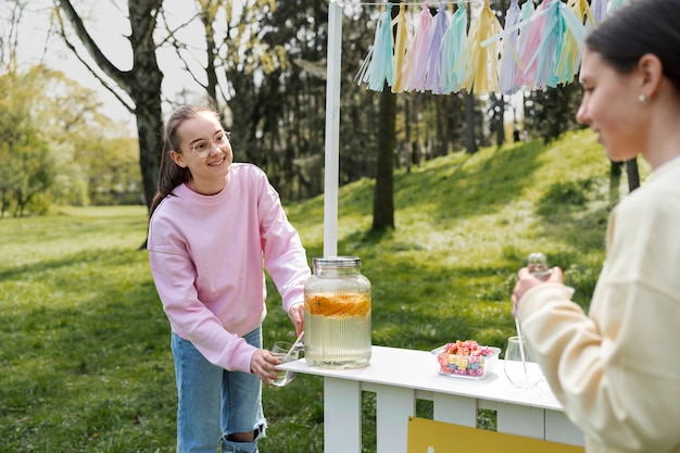 Free photo side view girl selling fresh lemonade