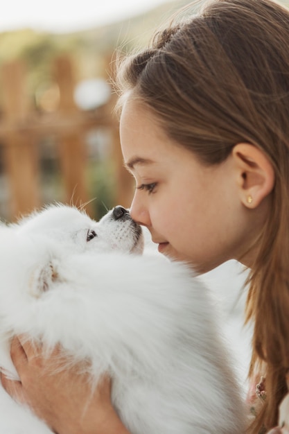 Free Photo side view girl touching noses with her dog