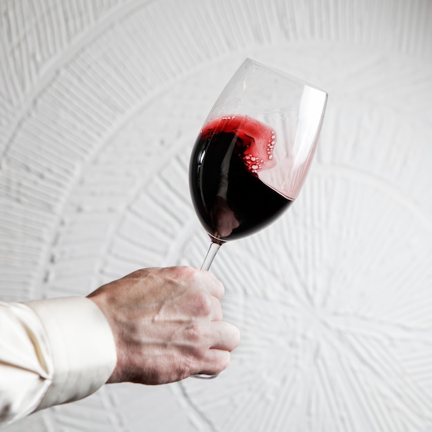 Side view glass of red wine with human hand