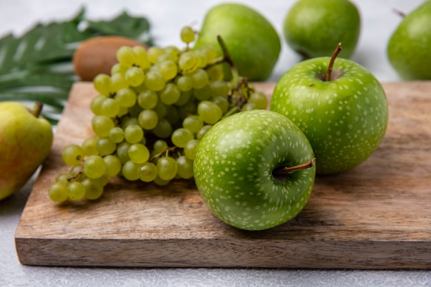 Side view green apples with green grapes on a stand  on a white background