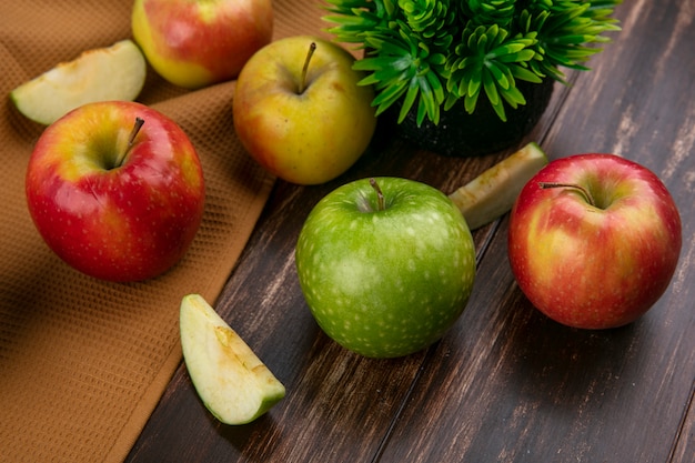 Side view green and red apples on a brown towel on a wooden background