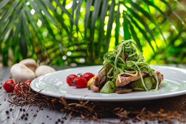 Free photo side view grilled chicken with tomato zucchini mushrooms and cucumber on a plate