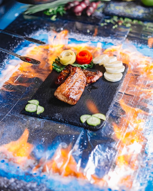 Free photo side view grilled fish fillet with lemon and cucumber on a tray