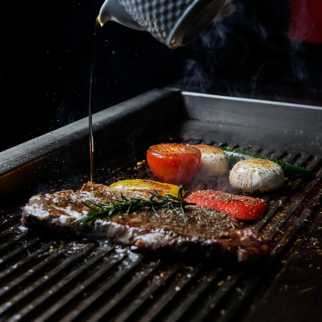 Side view grilled steak with rosemary and oil and mushrooms in barbecue