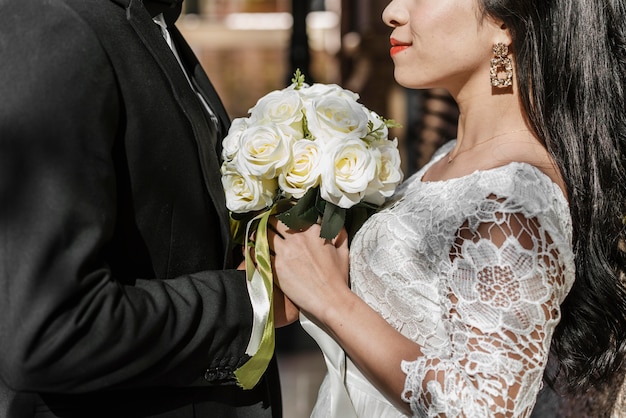 Side view of groom and bride holding bouquet of flowers