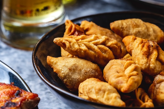 Side view gurza fried lamb dumplings with onion salt and pepper on a plate