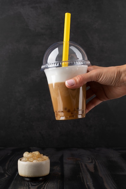 Free photo side view hand holding bubble tea cup