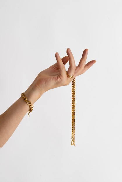 Free photo side view hand holding gold chain