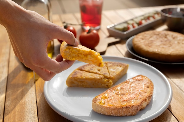 Free Photo side view hand holding spanish tortilla