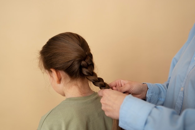 Free Photo side view hands braiding girl's hair