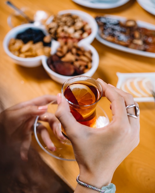 Side view of hands holding armudu glass with black tea