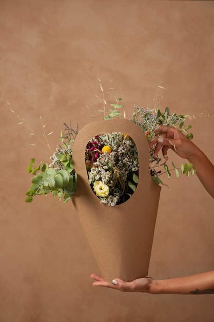 Side view hands holding basket with flowers