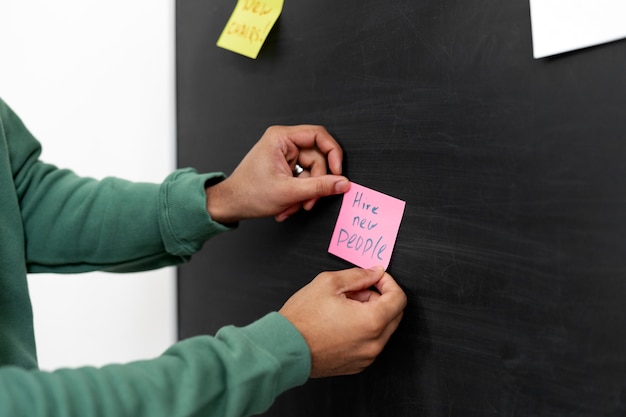 Free photo side view hands holding post it