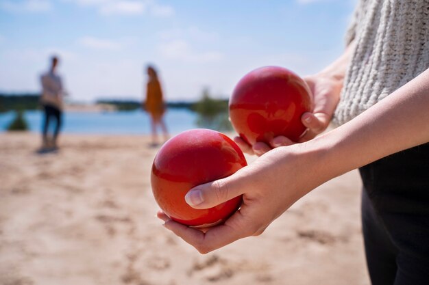 Side view hands holding red balls at beach