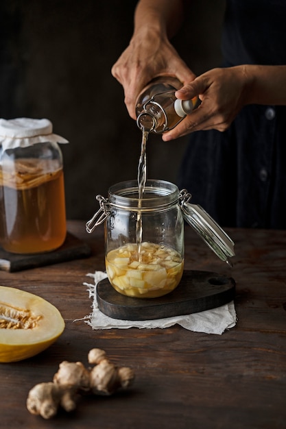 Free Photo side view hands pouring kombucha in jar