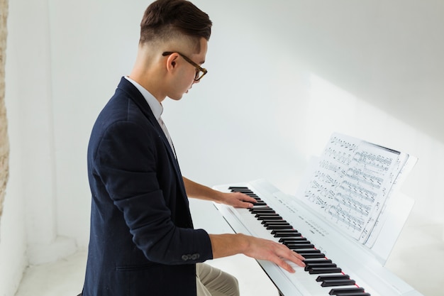 Free Photo side view of a handsome young man playing the piano