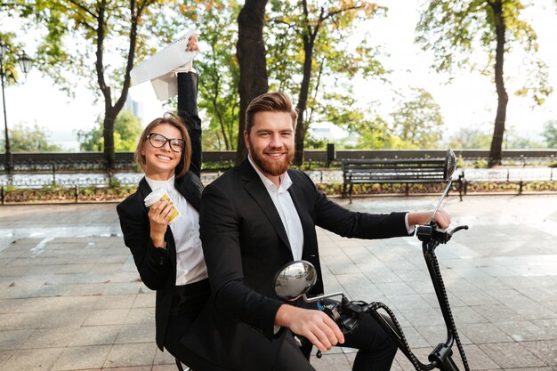 Side view of happy elegant couple rides on modern motorbike