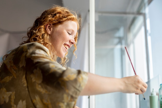 Free Photo side view happy woman holding a brush