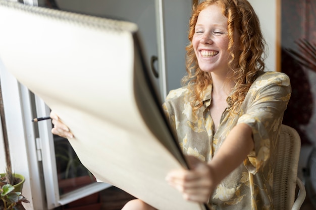 Free photo side view happy woman looking at sketchbook