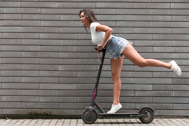 Free photo side view of happy woman posing on electric scooter