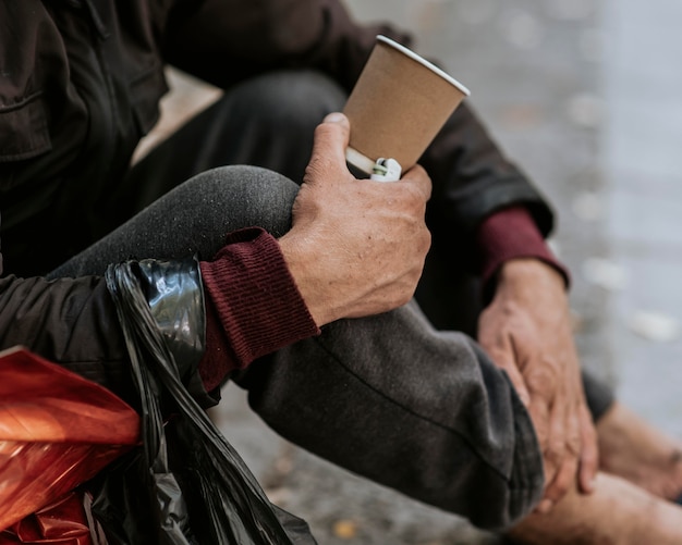 Free photo side view of homeless man holding cup