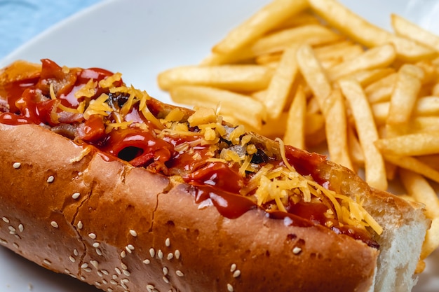 Free Photo side view hot dog grilled sausage with caramelized onion cheese ketchup and french fries on the table