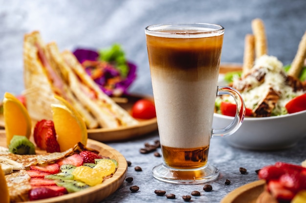 Side view hot drink with coffee milk honey and coffee beans on the table