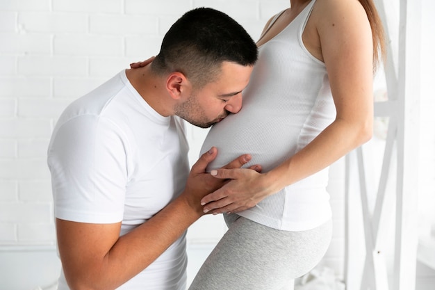 Side view husband kissing his wife's belly