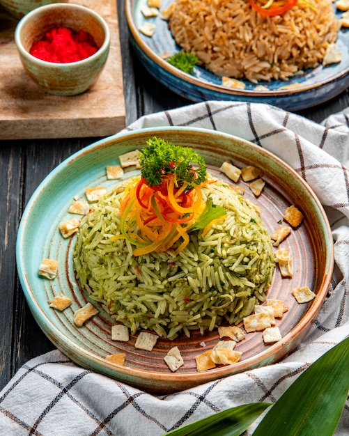 Free photo side view of japanese rice with vegetables on a plate on wooden surface