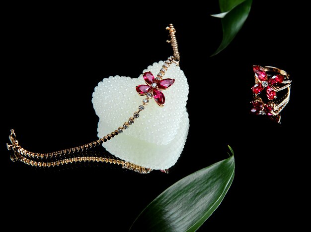 Side view of jewellery set of golden bracelet and rind with diamonds and rubies in a shape of butterfly