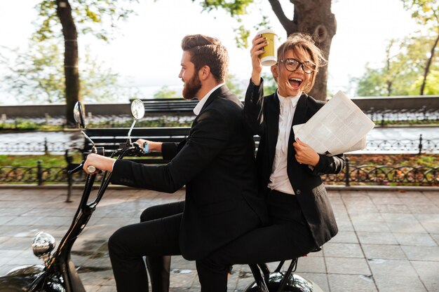 Side view of joyful elegant couple rides on modern motorbike