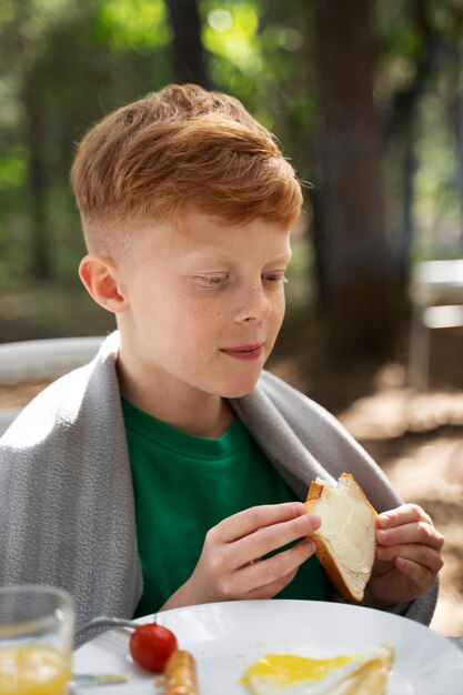 Side view kid eating in nature