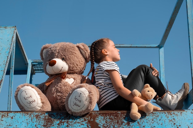 Free Photo side view kid holding teddy bear outdoors