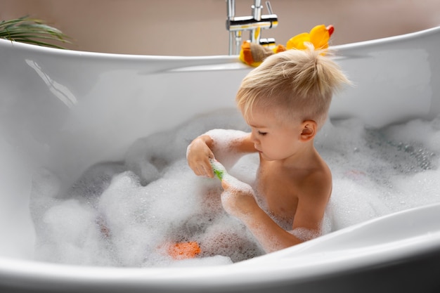 Side view kid playing in bathtub