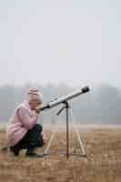 Free photo side view kid using a telescope outside